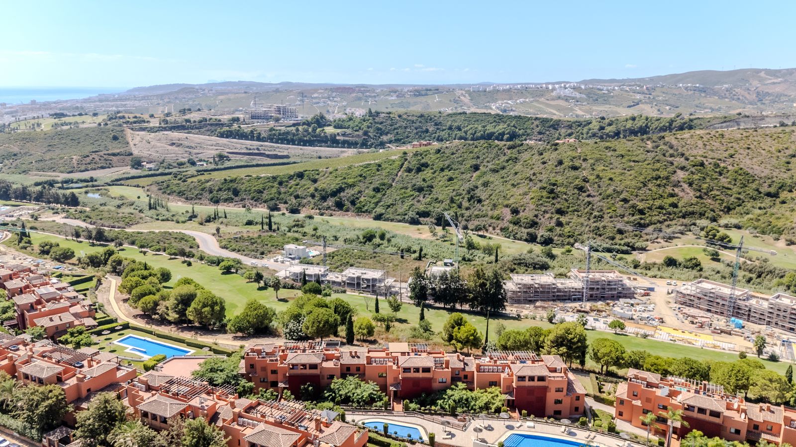 Wide aerial view across Casares Costa Golf and the surrounding green valley and hills